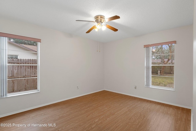 empty room with ceiling fan, light hardwood / wood-style flooring, and a textured ceiling