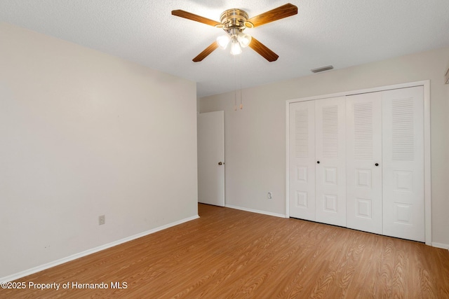 unfurnished bedroom featuring a textured ceiling, light hardwood / wood-style flooring, a closet, and ceiling fan