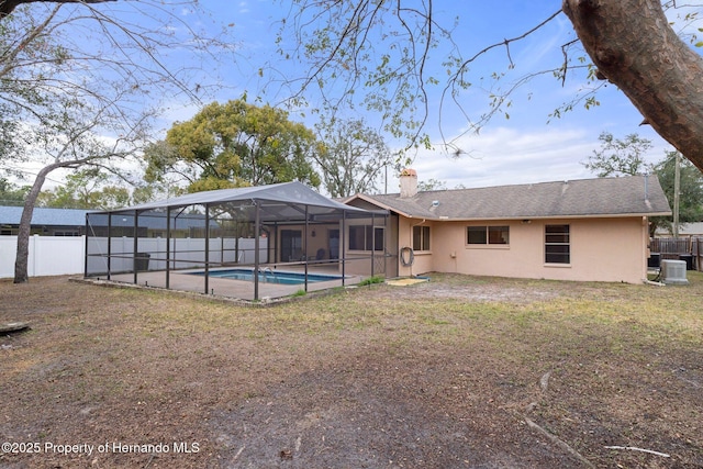 back of house featuring glass enclosure, a fenced in pool, central AC, and a yard