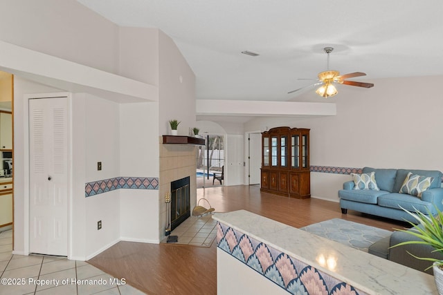 tiled living room featuring a tile fireplace and ceiling fan