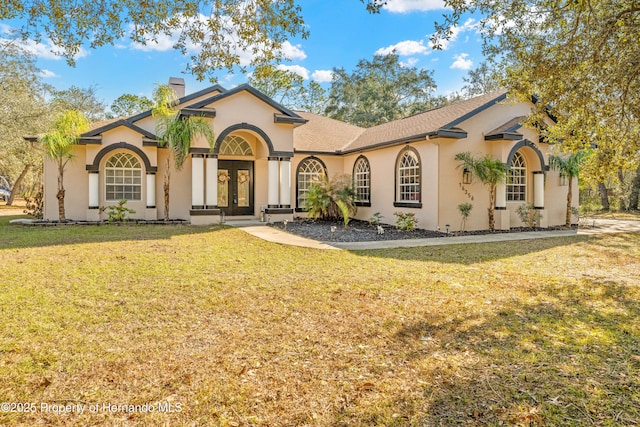 mediterranean / spanish house featuring a front yard and french doors