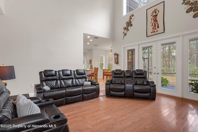 living room featuring wood-type flooring, a high ceiling, and french doors