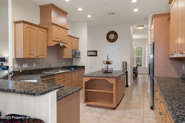 kitchen with sink, dark stone counters, a center island, and stainless steel appliances