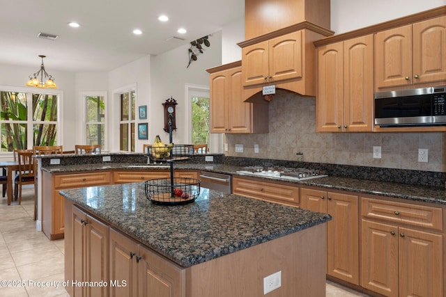 kitchen with pendant lighting, a kitchen island, dark stone counters, and appliances with stainless steel finishes