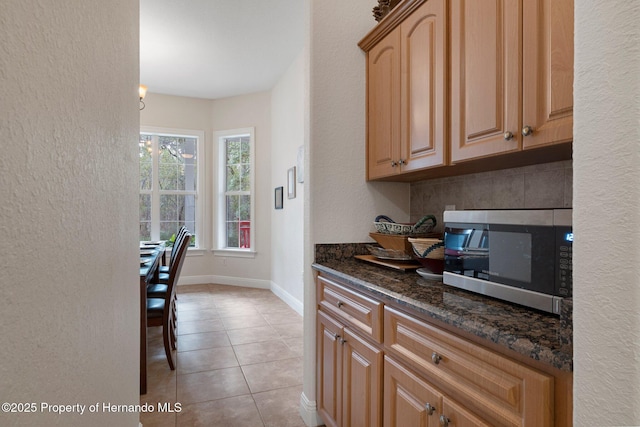 kitchen featuring dark stone countertops, tasteful backsplash, and light tile patterned flooring