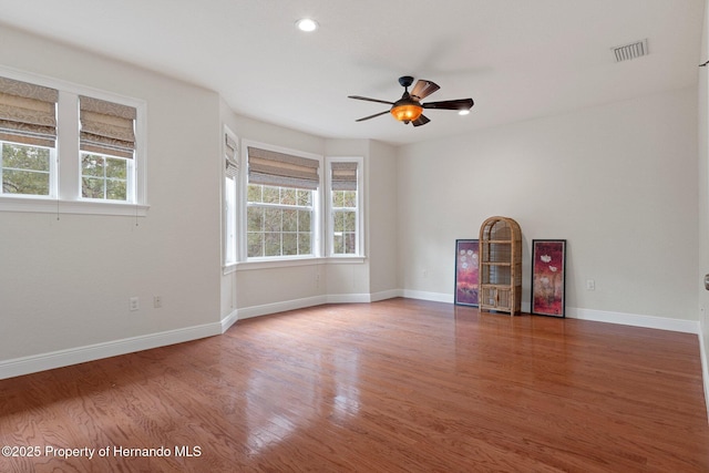 empty room featuring ceiling fan, hardwood / wood-style floors, and a wealth of natural light