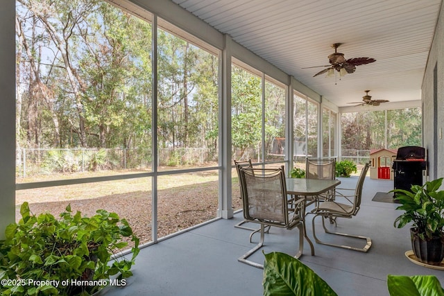 unfurnished sunroom featuring ceiling fan and plenty of natural light