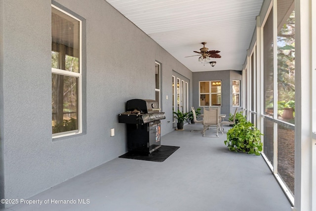 unfurnished sunroom featuring ceiling fan and plenty of natural light