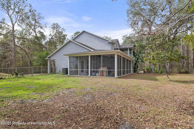 rear view of house with a sunroom, a yard, and central AC