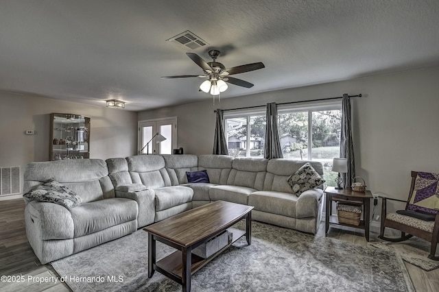 living room with dark hardwood / wood-style flooring, a textured ceiling, and ceiling fan