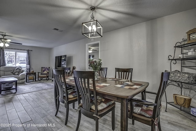 dining area with a textured ceiling and ceiling fan with notable chandelier