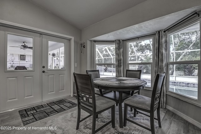 dining area with wood-type flooring, ceiling fan, vaulted ceiling, and plenty of natural light