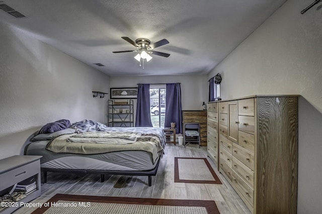 bedroom featuring a textured ceiling, ceiling fan, and light hardwood / wood-style flooring