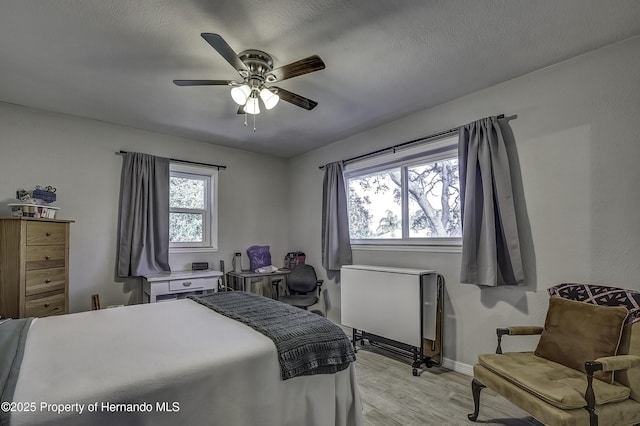 bedroom featuring a textured ceiling, ceiling fan, and light hardwood / wood-style flooring