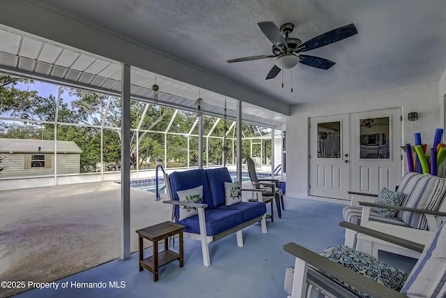 view of patio featuring ceiling fan, glass enclosure, and an outdoor living space