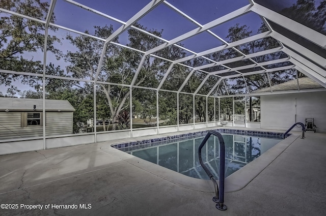 pool at dusk with a lanai and a patio area