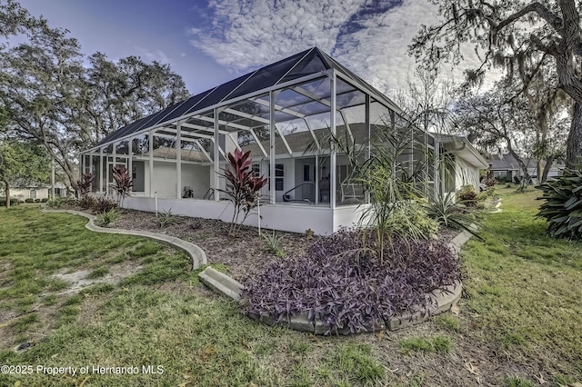 back of property featuring a lawn and glass enclosure