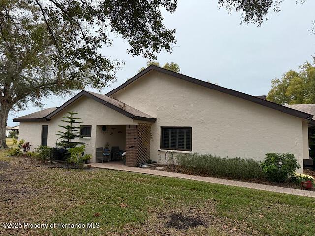 back of property with a patio area, a lawn, and stucco siding