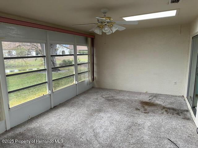 unfurnished sunroom featuring visible vents and a ceiling fan