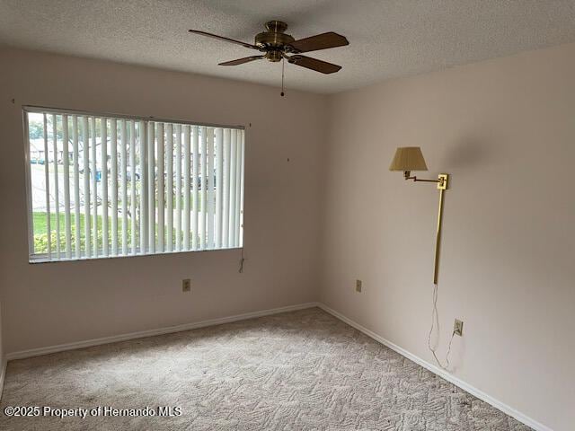 empty room featuring a ceiling fan, light carpet, a textured ceiling, and baseboards