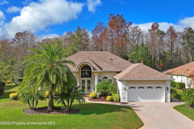 view of front facade featuring french doors, a front yard, and a garage