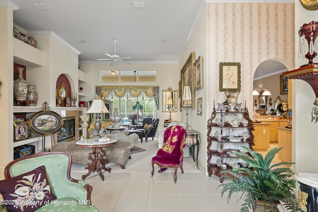 tiled living room with built in features, ceiling fan, and crown molding