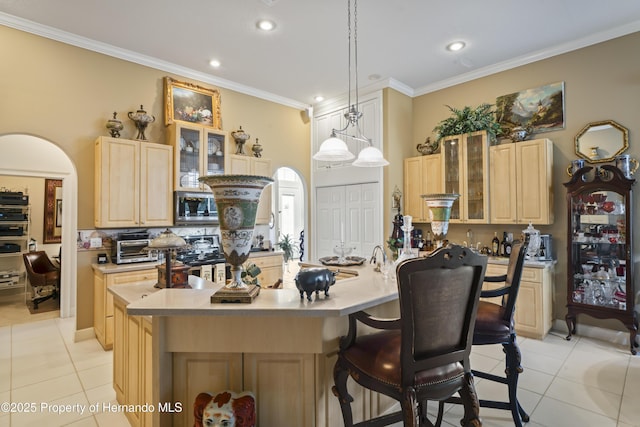 kitchen with decorative light fixtures, stainless steel appliances, light tile patterned flooring, and light brown cabinets