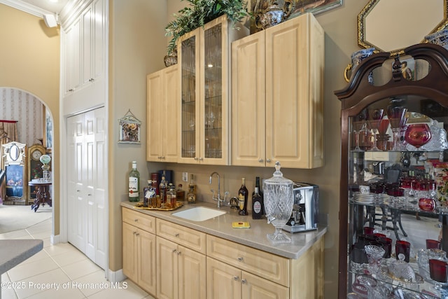 kitchen with sink, light tile patterned flooring, light brown cabinetry, and crown molding