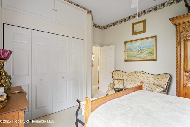 bedroom with ceiling fan, light colored carpet, and a closet