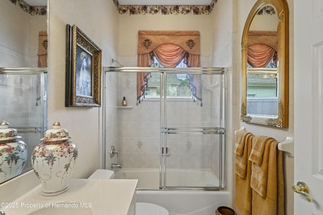 full bathroom featuring combined bath / shower with glass door, vanity, and toilet