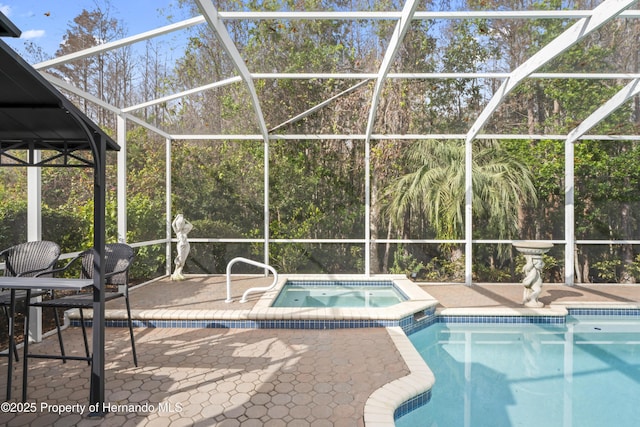 view of pool with a lanai, an in ground hot tub, and a patio area