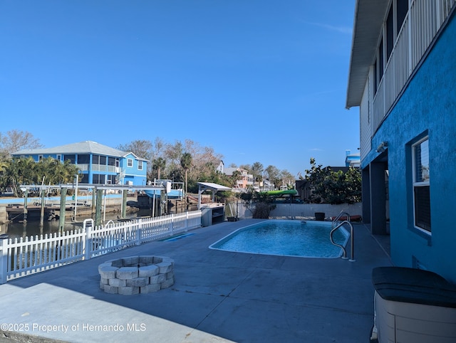 view of swimming pool featuring a water view, an outdoor fire pit, and a patio area