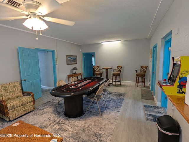 playroom featuring ceiling fan, wood-type flooring, and ornamental molding