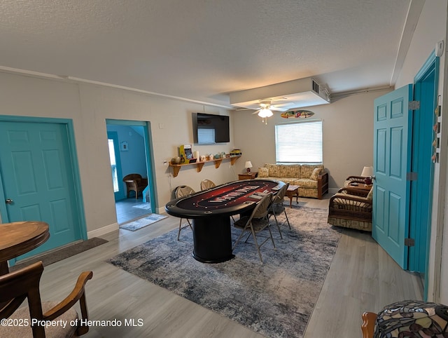 game room featuring ceiling fan, a textured ceiling, and light wood-type flooring