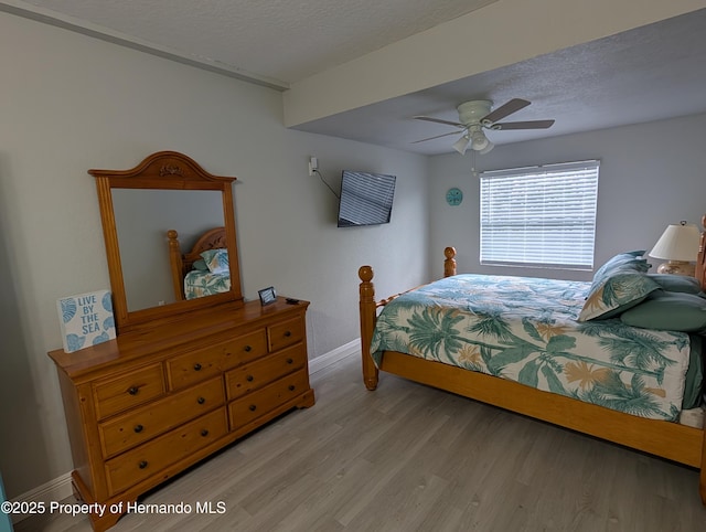 bedroom with ceiling fan, a textured ceiling, and light hardwood / wood-style flooring