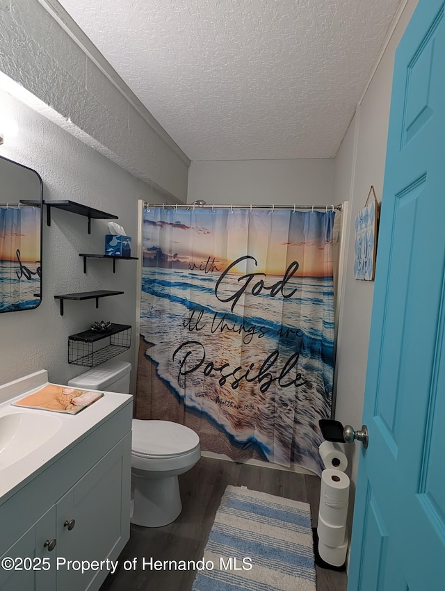 bathroom featuring vanity, toilet, hardwood / wood-style floors, and a textured ceiling