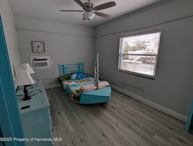 bedroom featuring hardwood / wood-style flooring, ceiling fan, a wall unit AC, and a textured ceiling