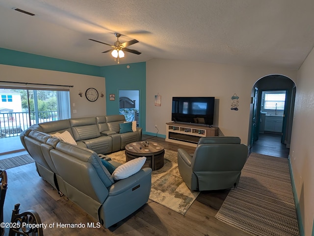 living room featuring ceiling fan, vaulted ceiling, sink, hardwood / wood-style flooring, and a textured ceiling