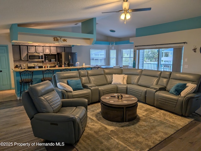 living room with ceiling fan, vaulted ceiling, and dark hardwood / wood-style flooring