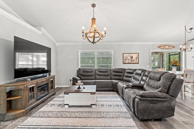 living room with vaulted ceiling, a chandelier, ornamental molding, and plenty of natural light