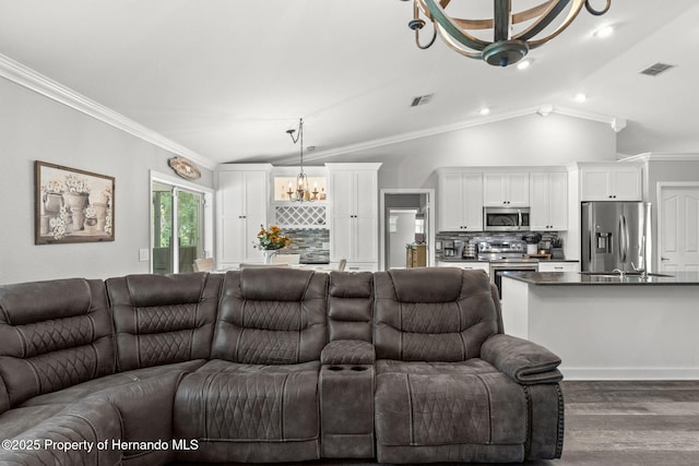 living room with vaulted ceiling, dark wood-type flooring, ornamental molding, and a notable chandelier