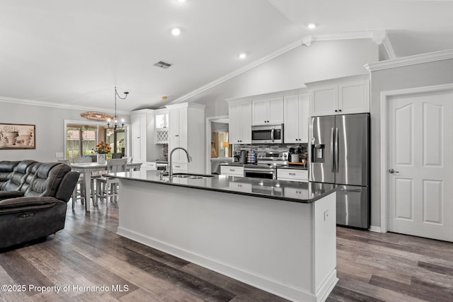 kitchen featuring white cabinets, decorative light fixtures, stainless steel appliances, sink, and vaulted ceiling