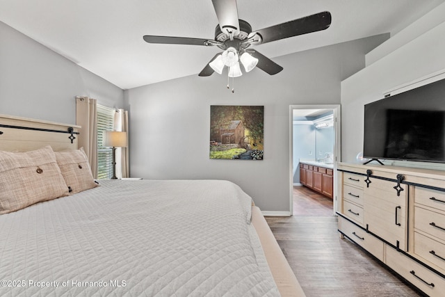 bedroom featuring ceiling fan, vaulted ceiling, dark hardwood / wood-style floors, and connected bathroom