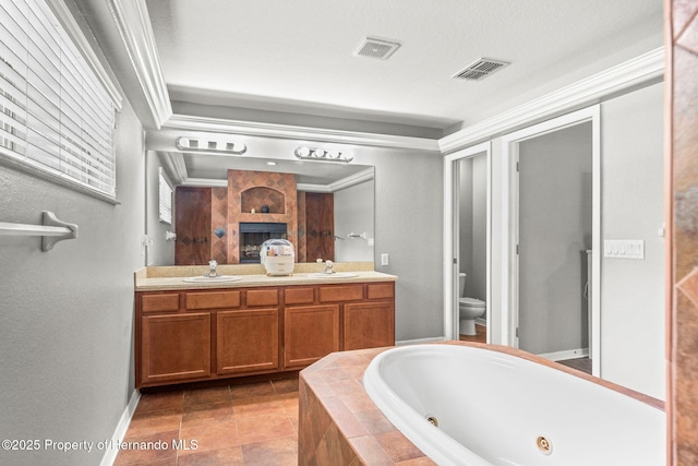 bathroom with tiled tub, tile patterned floors, vanity, toilet, and crown molding