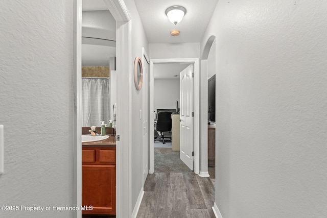 hall with sink, hardwood / wood-style floors, and a textured ceiling