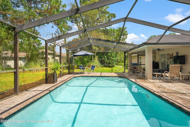 view of pool featuring ceiling fan, glass enclosure, and a patio area