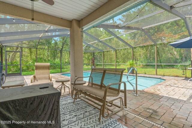 view of swimming pool featuring ceiling fan, glass enclosure, and a patio