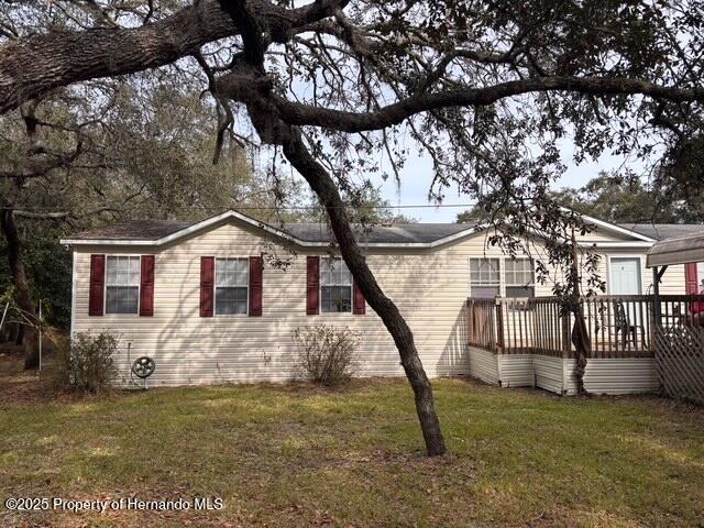 view of side of home featuring a lawn and a deck