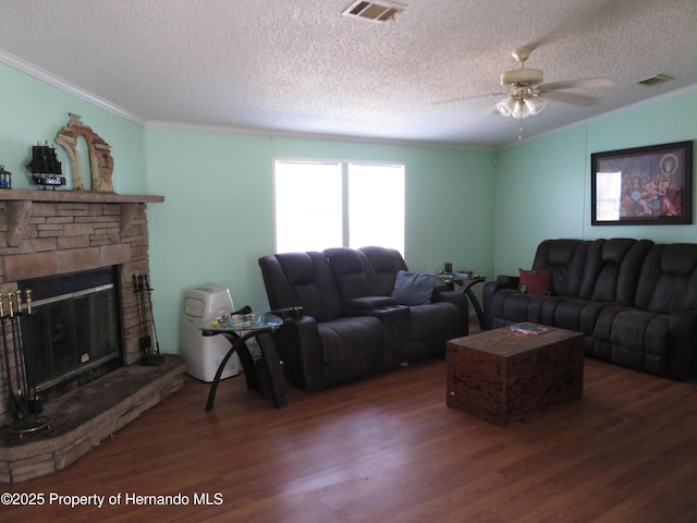 living room with dark hardwood / wood-style flooring, a stone fireplace, ornamental molding, and a textured ceiling