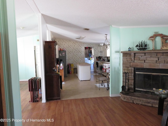 living room featuring a stone fireplace, wood-type flooring, washer / dryer, and a textured ceiling